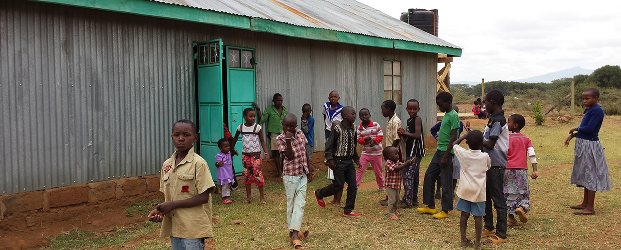 AIC Namuncha Child Development Center of Kenya children playing in front of water retention rain barrel